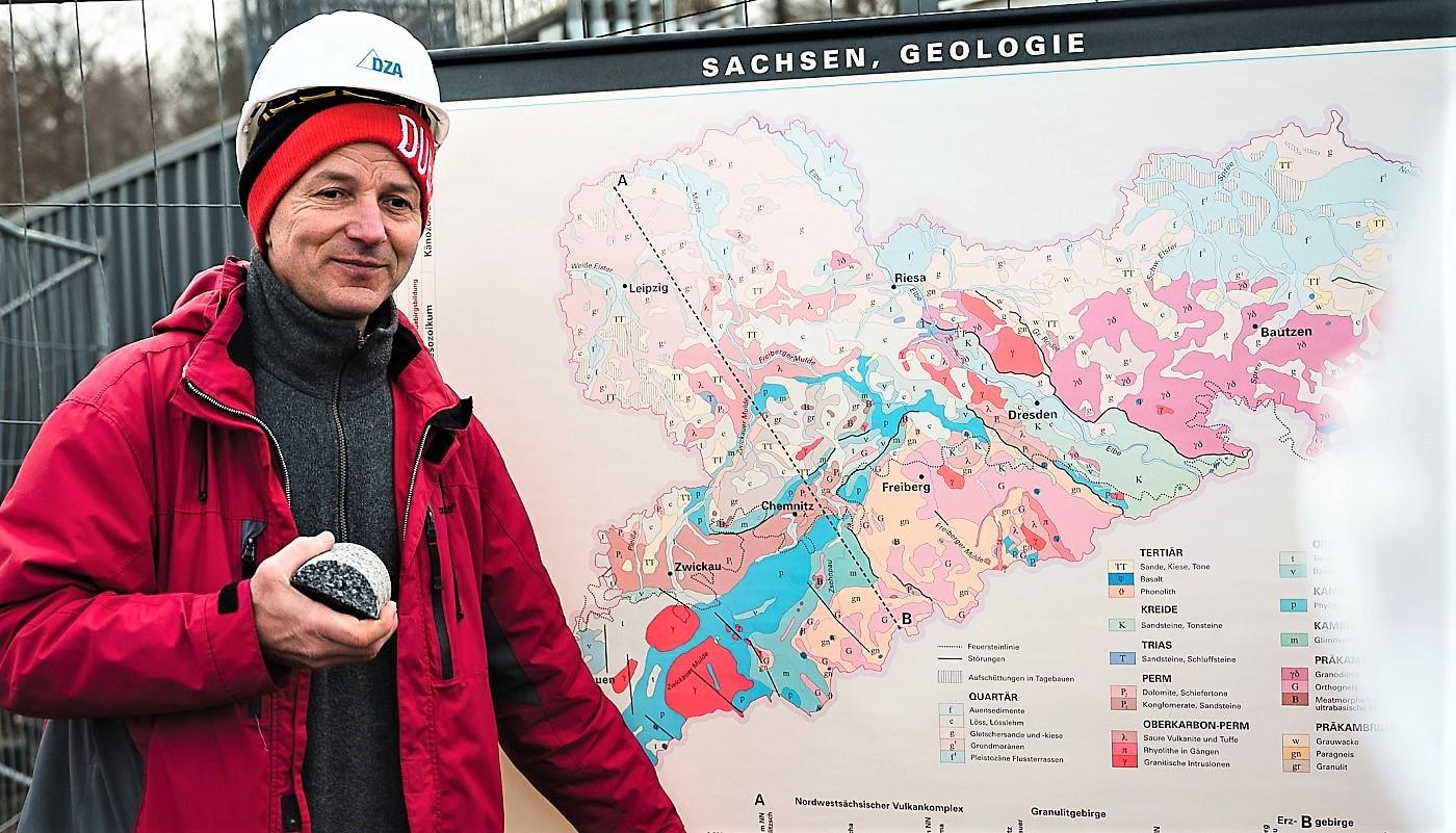 Mann mit weißem Schutzhelm steht vor einer geologischen Karte Sachsens