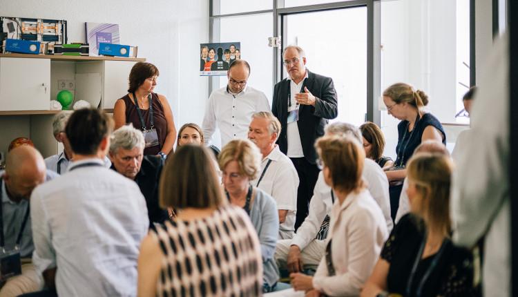 Mehrere Personen sitzen vor gläserner Wand